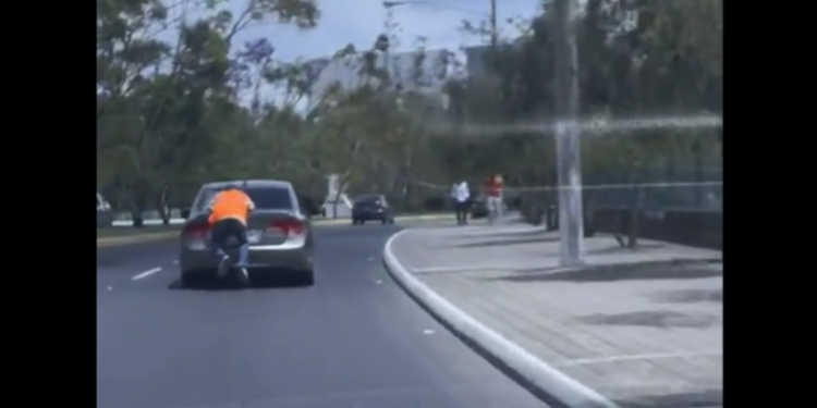 Graban a cuidador de parqueos montado en un carro que iba en marcha