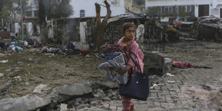 Niña palestina carga a su hermana herida en busca de ayuda médica en Gaza